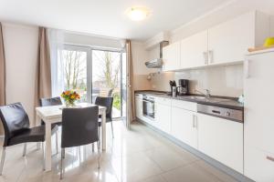 a kitchen with white cabinets and a table with chairs at Strandhaus Manatee mit Sauna und Kamin in Ostseebad Sellin +40 photos