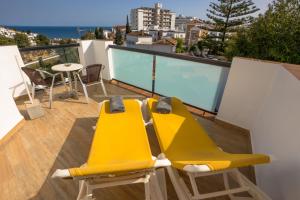 a balcony with two yellow chairs and a table at Hostal Casa Mercedes in Nerja