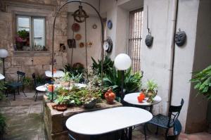 a patio with tables and chairs and potted plants at Pensió Bellmirall in Girona