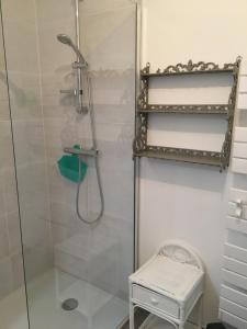 La salle de bains est pourvue d'une douche avec une porte en verre et un tabouret. dans l'établissement Gîte horizon mer et campagne, à Pornic