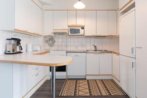 une cuisine avec des placards blancs et une table en bois dans l'établissement Torget Apartment Laululinna, à Pori