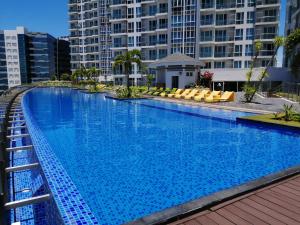 a large swimming pool with yellow chairs and buildings at Mactan Newtown Deluxe Island Breeze in Mactan