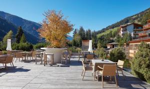 a patio with tables and chairs and mountains in the background at Arosea Life Balance Hotel in Santa Valburga St. Walburg