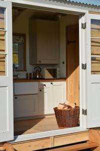 una cucina con armadietti bianchi e un cesto di Snug Oak Hut with a view on a Welsh Hill Farm a Brecon