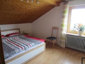 ein Schlafzimmer mit einem Bett, einem Fenster und einem Stuhl in der Unterkunft Weingut Arnold Pauly in Osann-Monzel