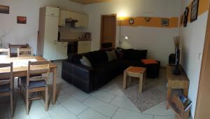 a living room with a black couch and a kitchen at Ferienwohnung Am Rauenstein in Struppen