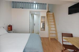 1 dormitorio con cama, escalera y mesa en Casa da Avó Lurdes, en Póvoa de Varzim