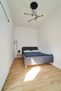 1 dormitorio con 1 cama en una pared blanca en Apartamenty Muzyczna 14, en Suwałki