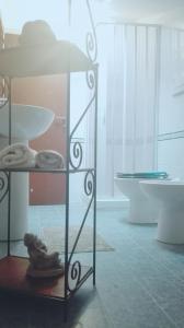 un bagno con mensola in vetro, lavandino e vasca di Casa del Loto a Fiumicino