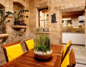 a wooden table with yellow chairs and a pot on top at The 3Cities Auberge in Cospicua