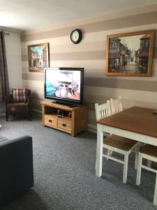 倫敦的住宿－Lovely One Bedroom Apartment in Stratford，客厅配有平面电视和桌子。