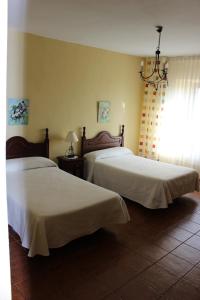 a bedroom with two beds and a chandelier at La Cuarta in Herrera de Pisuerga