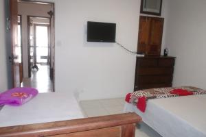 格雷夫森德的住宿－Boullevard Villa da Serra，一间卧室设有两张床,墙上配有电视。