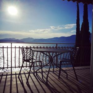 2 Stühle und ein Tisch auf einer Terrasse mit Blick auf das Wasser in der Unterkunft Residenza Bellavista Eremitaggio in Torri del Benaco