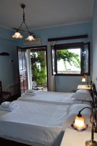 a bedroom with two beds and two windows at Ilion Hotel in Nafpaktos