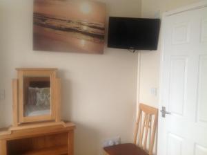 Zimmer mit einem TV an der Wand und einem Stuhl in der Unterkunft Crossways Tavern in Exeter