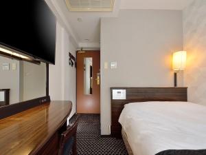 a hotel room with a bed and a flat screen tv at APA Hotel Yokohama Kannai in Yokohama