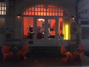 a room with orange chairs in front of a door at B&B Geste d' Alice in Middelkerke