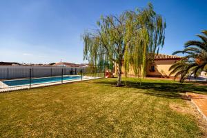 um quintal com uma árvore e uma piscina em Villa Cíes em Chiclana de la Frontera