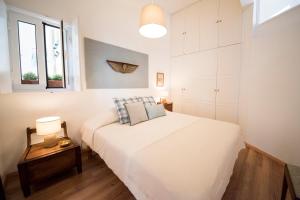 a white bedroom with a bed and a table and windows at Light Lovers Apartment in Lisbon