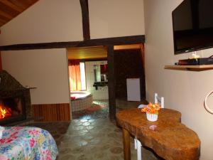 sala de estar con chimenea, cama y mesa en Pousada Chalés Vista da Serra, en Visconde De Maua