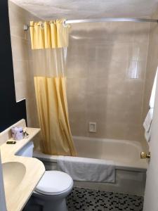 a bathroom with a yellow shower curtain and a toilet at Advance Inn in Niagara Falls