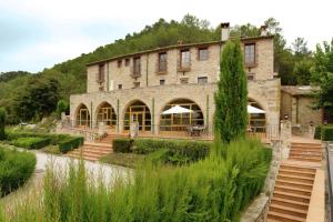 Un grand bâtiment en pierre avec des escaliers se trouve juste devant. dans l'établissement Can Mas Albanyà, à Albanya