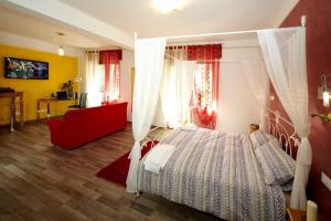 1 dormitorio con cama con dosel y sofá rojo en Locanda Da Luca, en Recoaro Terme