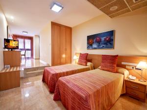 ein Hotelzimmer mit 2 Betten und einem TV in der Unterkunft Hotel Anna in Cocentaina
