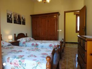 a bedroom with two beds and a wooden cabinet at Tertenia Centro in Tertenìa