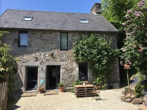 a stone house with a table and benches in front of it at Chez Natacha et Adrien in Regnéville-sur-Mer