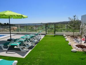 een patio met stoelen, een parasol en gras bij Villa Ria Alvor- Swimming pool & Jacuzzi in Alvor