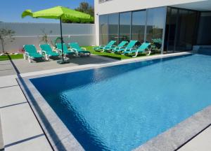 een zwembad met stoelen en een parasol bij Villa Ria Alvor- Swimming pool & Jacuzzi in Alvor