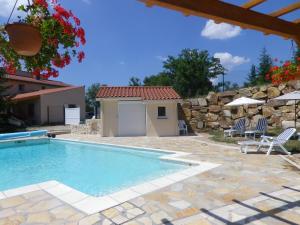 a swimming pool in a yard with a stone wall at Le Panorama - Chambres d'hôtes - Cuisine disponible in Vieille-Brioude