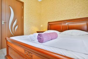 a bed with a wooden headboard and a purple blanket at Apartment Anano in Kutaisi