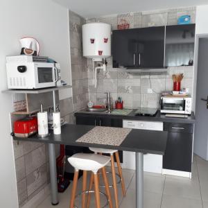 una pequeña cocina con encimera negra y microondas en Studio avec jardinet clim parking, en Gruissan