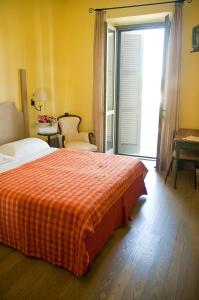 a bedroom with a bed with a orange blanket and a window at Locanda Delle Mura Anna De Croy in Magliano in Toscana