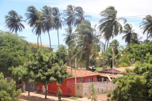 a red house in a forest with palm trees at Flat's Portal do Sol-SMG in São Miguel do Gostoso