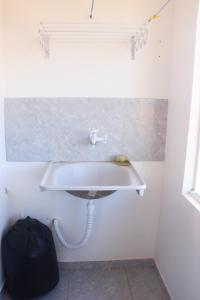 a white sink in a bathroom with a black bag at Flat's Portal do Sol-SMG in São Miguel do Gostoso +26 photos
