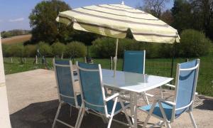 a table and four chairs with an umbrella at La maison de Mathilde in Saint-Jean-de-la-Motte