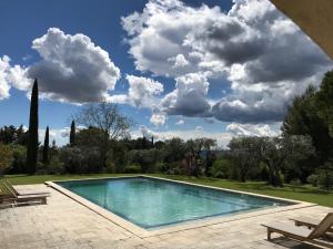 a swimming pool in a yard with a cloudy sky at LES BARTAVELLES in Aix-en-Provence +12 photos