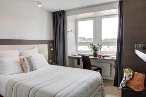 Habitación de hotel con cama, escritorio y ventana en Le Benhuyc, en Binic