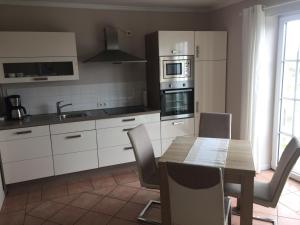 una cocina con mesa de madera y una cocina con armarios blancos. en Strandvilla Kalifornien direkt am Meer en Kalifornien