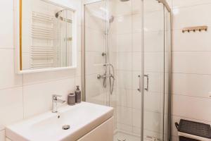 y baño blanco con lavabo y ducha. en Apartament w centrum Olsztyna - Grunwaldzka, en Olsztyn