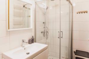 Un baño blanco con lavabo y ducha. en Apartament w centrum Olsztyna - Grunwaldzka, en Olsztyn 3 fotos más