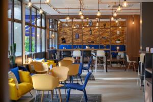 um restaurante com mesas e cadeiras amarelas e azuis em Tulip Inn Antwerpen em Antuérpia