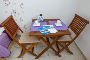 drewniany stół z dwoma krzesłami i książką na nim w obiekcie Apartments Vesela w mieście Seline