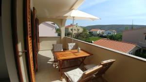 a balcony with a wooden table and an umbrella at Apartments Vlasici in Vlašići