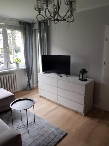 un soggiorno con TV a schermo piatto su una cassettiera bianca di Apartament Okrzei a Kłodzko