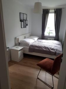 a bedroom with a bed and a chair and a window at Apartament Okrzei in Kłodzko